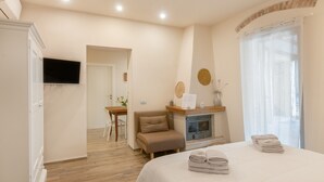 Una habitación de hotel con cama, chimenea, televisor y comedor.