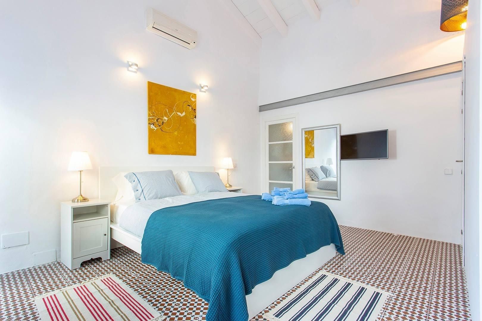 Une chambre à coucher avec un lit, des tables de chevet, une télévision et une grande fenêtre.