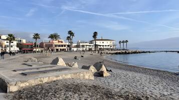 Una playa con edificios, palmeras y un litoral rocoso.