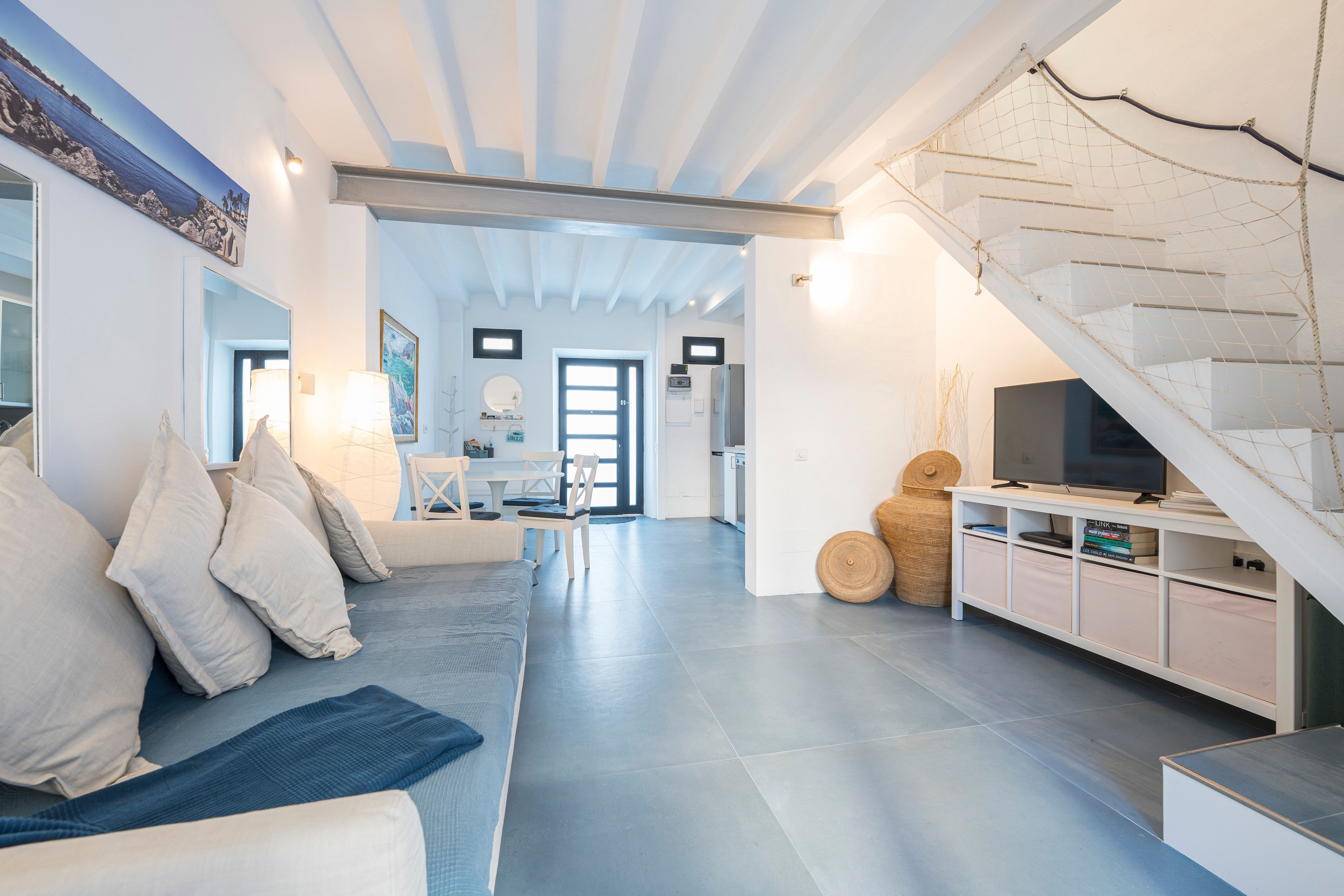 Una sala de estar moderna con sofá, televisor y una escalera.