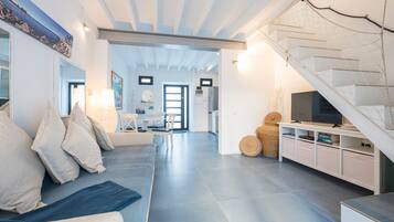 Una sala de estar moderna con sofá, televisor y una escalera.