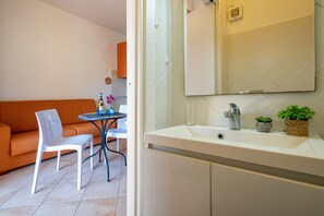 A modern bathroom with a large mirror, white sink, and two potted plants.
