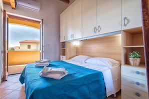 A bedroom with a bed, a nightstand, a wardrobe, and a balcony.
