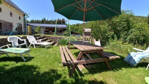 Een buitenruimte met een picknicktafel, stoelen en een grote parasol.