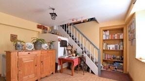 Een trap die leidt naar een kamer vol boeken, een houten kast met planten en een betegelde vloer.