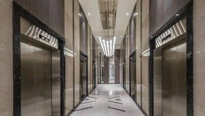 Un couloir moderne avec des portes en verre, un plancher poli et un luminaire central.
