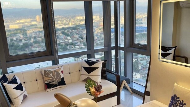 Un salon moderne comprenant un canapé, une table basse et une grande fenêtre donnant sur la ville.