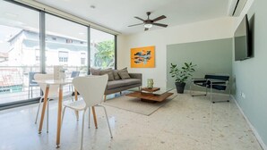 Een moderne woonkamer met een bank, stoelen, een salontafel, een televisie en een plafondventilator.