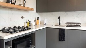 Eine moderne Küche mit Gasherd, Mikrowelle und Kaffeemaschine auf einem Holzboden.