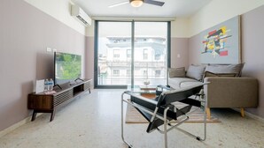 Een moderne woonkamer met een bank, een salontafel, een televisie en een plafondventilator.