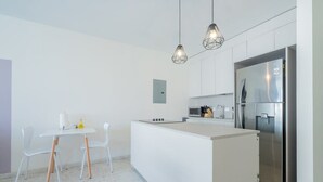 Een moderne keuken met een centraal eiland, witte kasten, roestvrijstalen apparatuur en hanglampen.