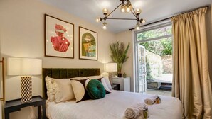 Un lit bien fait, avec des oreillers, une table de chevet avec une lampe et une grande fenêtre avec des rideaux.