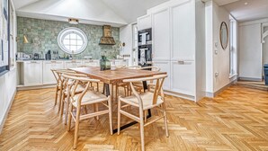 Una cucina moderna con pavimento a spina di pesce, mobili bianchi e una finestra rotonda sopra l'isola.