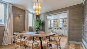 Un'area pranzo con tavolo e sedie in legno, un lampadario e vista sulla cucina.