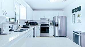 Una cocina moderna con armarios blancos, electrodomésticos de acero inoxidable y un diseño limpio y minimalista.