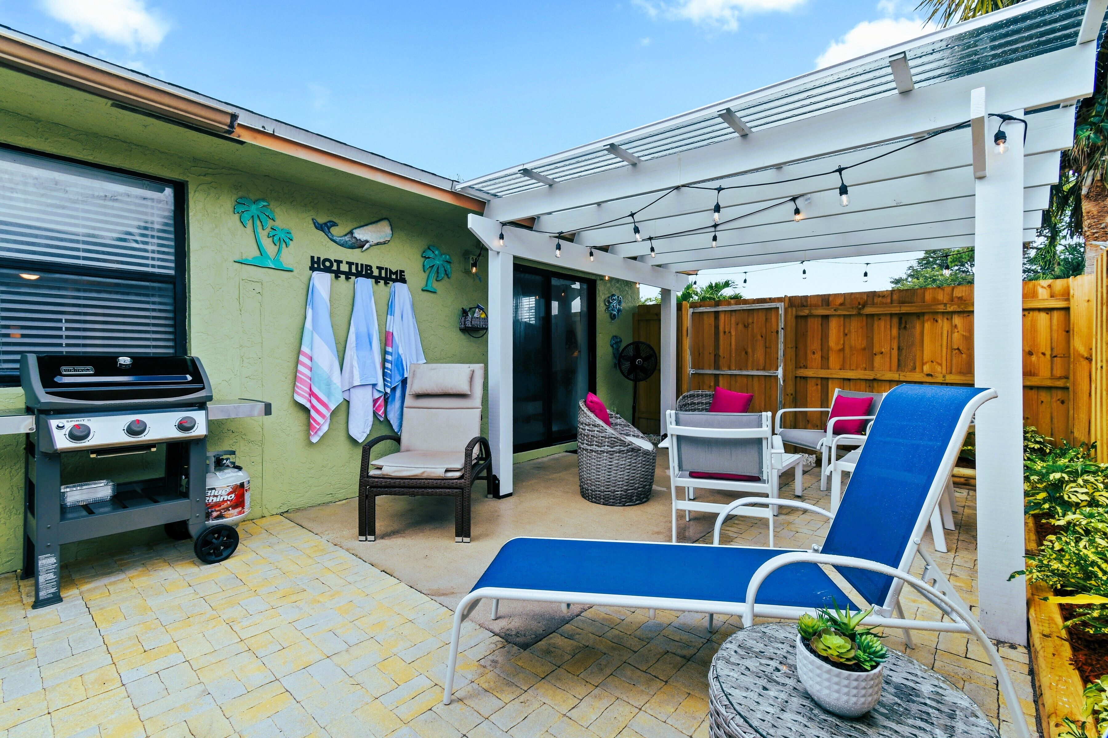 A patio area with a grill, outdoor seating, and a pergola.