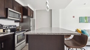 Eine moderne Küche mit dunklen Holzschränken, Edelstahlgeräten und einer Arbeitsplatte aus Granit.