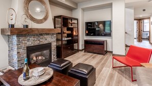 Una sala de estar moderna con chimenea, televisor y un sillón rojo.