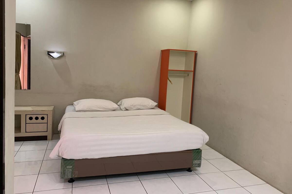 A bedroom with a bed, a nightstand, a mirror, and a wardrobe.
