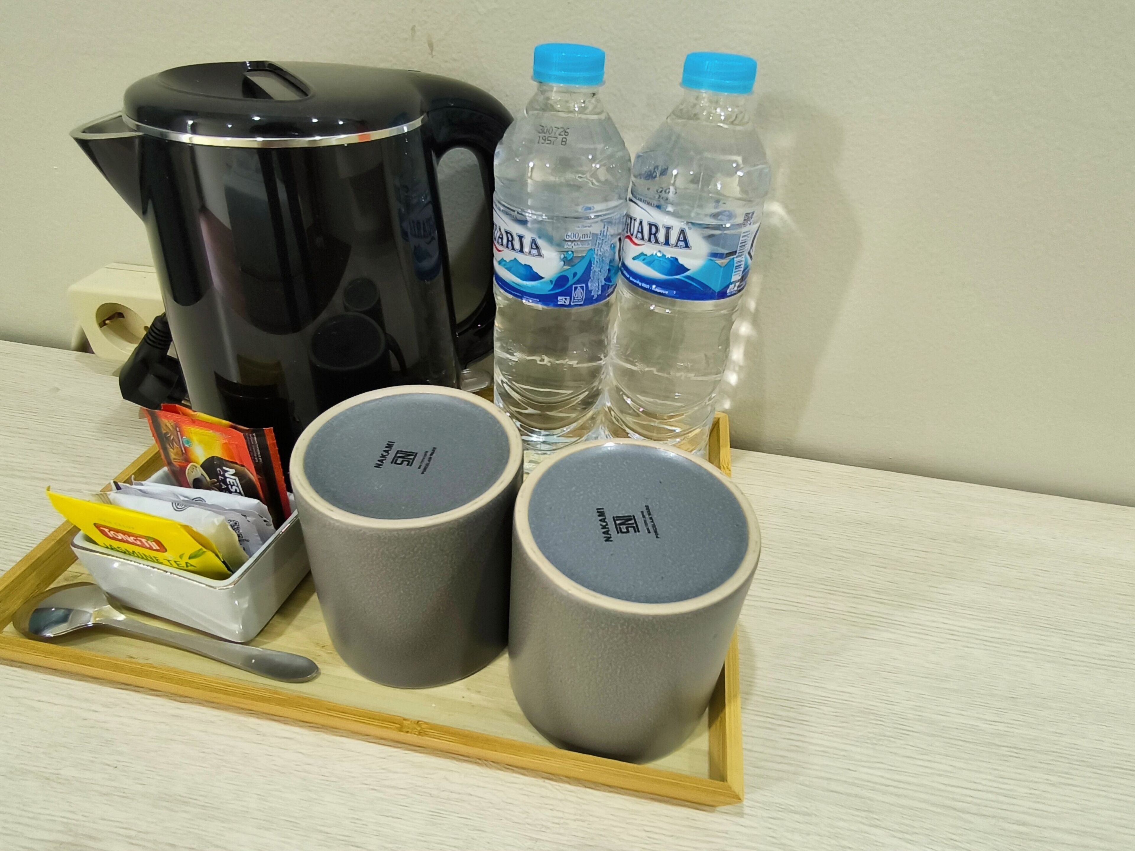 Un plateau avec une machine à café, deux bouteilles d’eau et trois tasses.