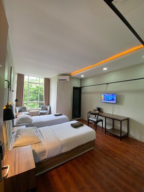 A hotel room with two beds, a desk, a TV, and a window with curtains. - Royal Kencana powered by Cocotel (Jepara)