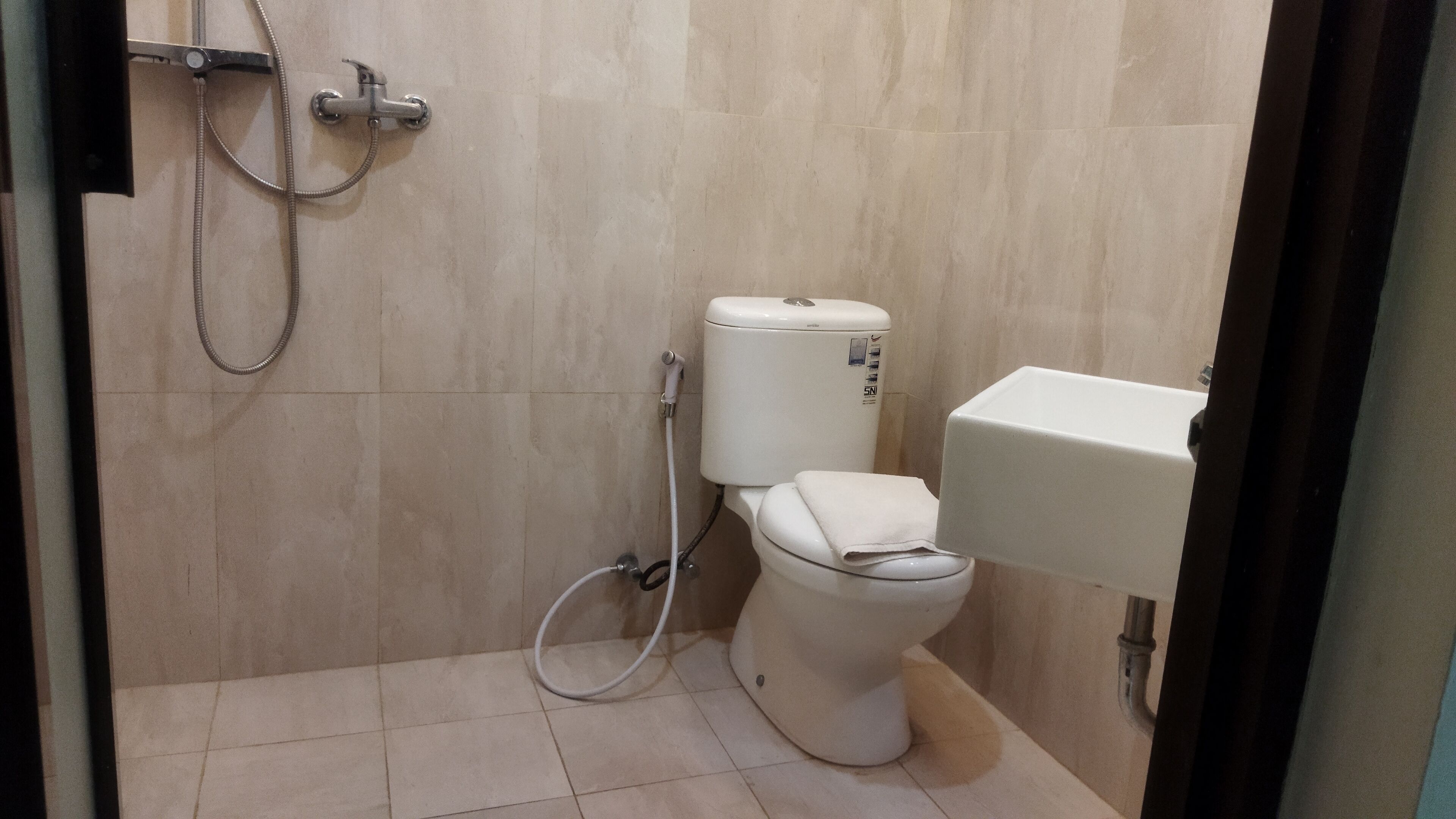 A small, tiled bathroom with a toilet, a shower, and a sink.
