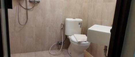 A small, tiled bathroom with a toilet, a shower, and a sink.