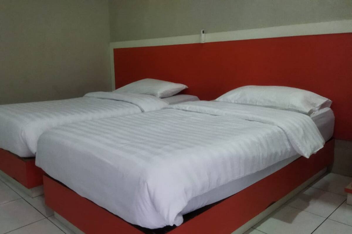 A double bed with white bedding in a room with red and white walls.