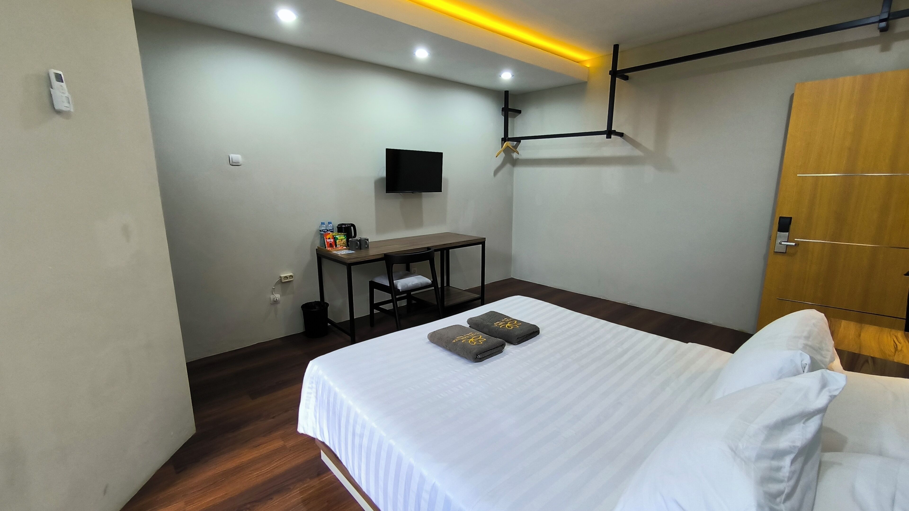 A hotel room with a bed, a desk, a chair, a TV, and a wooden wardrobe.