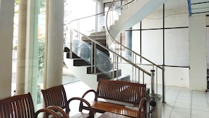 Un interior moderno con una escalera, bancos de madera y amplios ventanales.