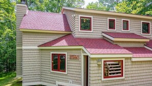 A two-story house with a red roof, beige siding, and red-framed windows. - Charming Okemo Home: Hot Tub, Fireplace, Sleeps 9 (Ludlow)