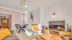 Ein modernes Wohnzimmer mit einer Couch, einem Holztisch, einem Fernseher und einem Essbereich mit Stühlen und einem Tisch.