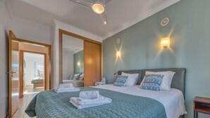 Ein Hotelzimmer mit einem großen Bett, zwei Nachttischen, einem Deckenventilator und Blick ins Freie.