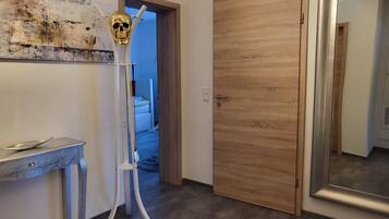 Ein Flur mit einer Holztür, einer weißen Wand mit einer strukturierten Malerei und einer Metallskulptur.