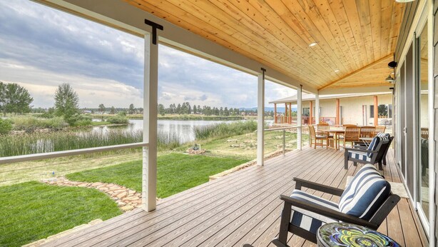 Eine überdachte Terrasse mit Blick auf einen See und eine Wiese.