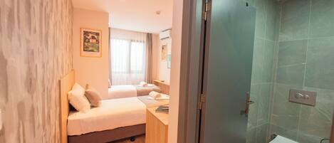 Una habitación de hotel con cama, mesita de noche y baño completo.