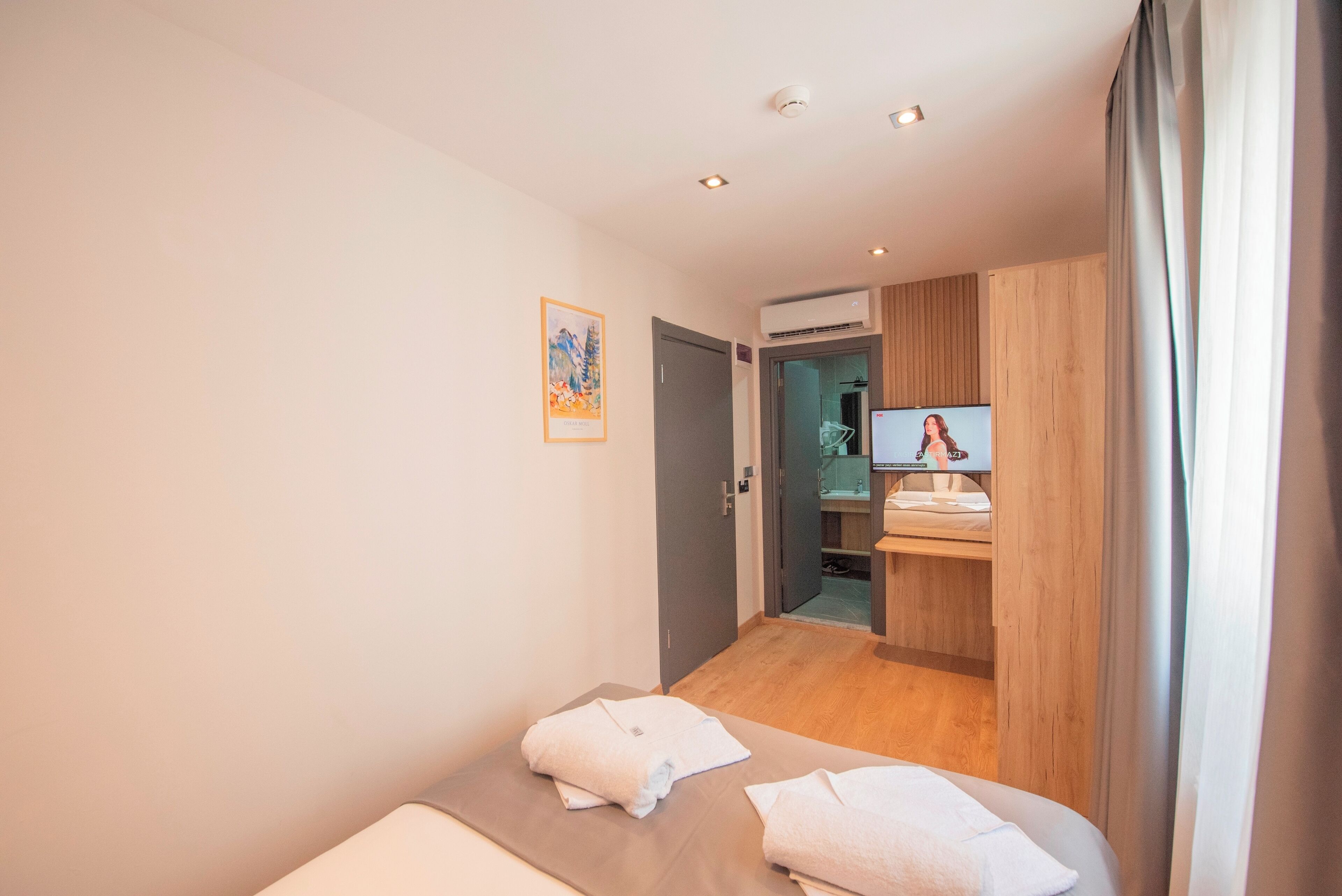 Una habitación de hotel con una cama, un baño y un escritorio pequeño con una computadora.