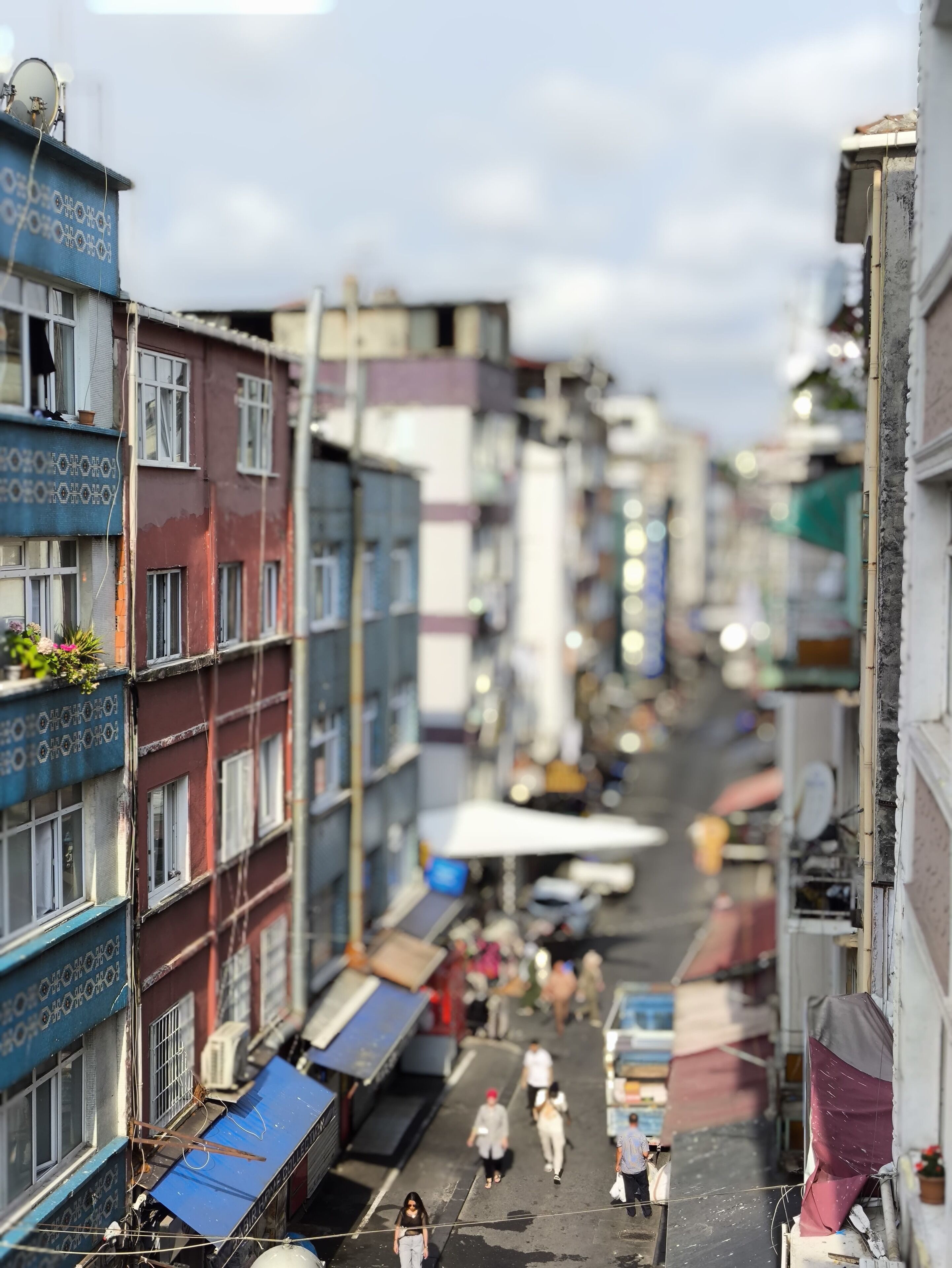 Une rue étroite bordée d’immeubles à plusieurs étages, dont certains sont dotés de balcons et de climatiseurs.