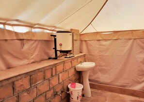 A tented bathroom with a sink, a toilet, and a water heater.