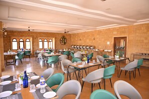 A spacious dining area with multiple tables and chairs, a brick wall, and a ceiling fan.