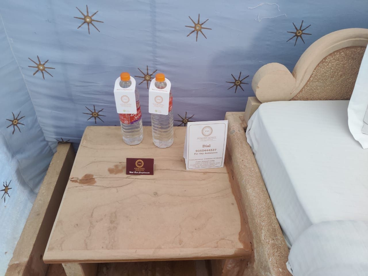 Ein Nachttisch aus Holz mit einer Wasserflasche und einer Zimmerschlüsselkarte.