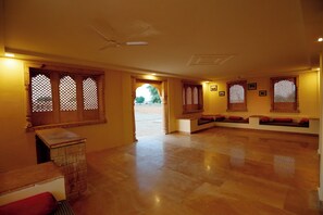 A spacious room with a wooden bench, a small table, and a door leading outside.