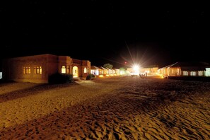 Un complexe hôtelier situé dans le désert, avec des bâtiments illuminés et un paysage sablonneux.