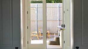 A door leading to an outdoor patio with a wooden fence, a yellow chair, and a water heater. - Cozy Modern Suite with Hot Tub (Fredericksburg)