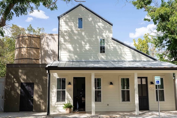 A white building with a black door, a small window, and a sign indicating reserved parking. - Cozy Modern Suite with Hot Tub (Fredericksburg)