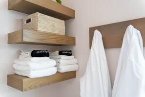 Ein Badezimmer mit Holzregalen, auf denen Handtücher und ein Korb liegen.