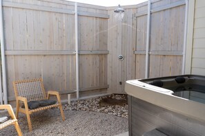 Une terrasse en bois avec un jacuzzi, une chaise et un espace douche.