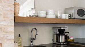 A kitchen with a sink, a microwave, a coffee maker, and a mirror above the counter. - Cozy Modern Suite with Hot Tub (Fredericksburg)