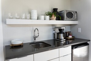 A modern kitchen with a black countertop, stainless steel appliances, and white cabinetry. - Cozy Suite with Hot Tub in Fredericksburg (Fredericksburg)