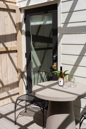 A patio with a round table, a chair, a bottle of wine, and a potted plant. - Cozy Suite with Hot Tub in Fredericksburg (Fredericksburg)
